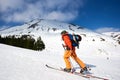 Ski touring man reaching the top in snow covered mountains, at sunny day Royalty Free Stock Photo