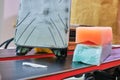 Ski wax iron and wax bars, colored orange and teal for different temperatures, laid on top of a pair of skis. Ski base tuning.