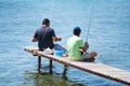 Two men sitting on small jetty fishing Royalty Free Stock Photo