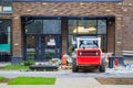 Skid loader stands in front of entrance to new multi-storey house and waits for garbage to be loaded into  bucket. Mini bulldozer Royalty Free Stock Photo