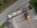Skid steer loader loading a truck with waste material, aerial view