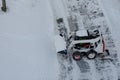 Skid steer loader removes snow from the city streets. Top view of the road with cars and snow blower. Seasonal work in winter Royalty Free Stock Photo