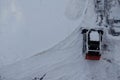 Skid steer loader removes snow from the city streets. Top view of the road with cars and snow blower. Seasonal work in winter Royalty Free Stock Photo