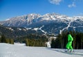 Skier in bright neon green outfit enjoying the view of winter landscape around at Madonna di Campiglio Ski Resort