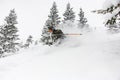 skier descending a snow-covered mountain slope and splash of snow around him