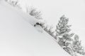 skier descends a steep snowy mountain slope and splashes of powder snow around him