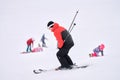 A skier goes down a snow-covered slope. In the background, blurry images of snowboarders. Selective focus