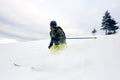 Skier in deep powder on snow-capped downhill. Extreme skiing concept. Grey sky and pine tree on background. Front view. Royalty Free Stock Photo