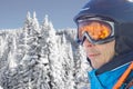 Skier man in the blue skiing jacket, helmet and glasses against snow forest panorama