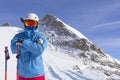 Skier man with orange ski glasses in white helmet make photoshoot on top in Alps mountains. On the background of mountains. Close