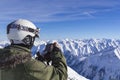 Skier man with orange ski glasses in white helmet make photoshoot on top in Alps mountains. On the background of Royalty Free Stock Photo