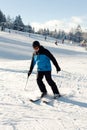 Skier man rides from the mountain with a cableway on background