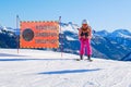 Skier posing in a race style position next to a ski piste sign saying Difficult Slope in German, Italian, and English
