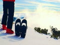 Skier in red winter jacket with fun snowshoes stay in snow in mountains.