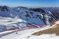 Skier riding along snowy ski slope of Gorky Gorod winter mountain ski resort on blue sky and snowy Caucasus peaks scenic Royalty Free Stock Photo