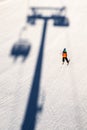 Skier and shadow of ski-lift chair on slope at ski resort