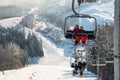 Skiers on cable car in Bukovel with background snow-covered slopes