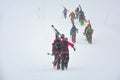 Skiers carries skis and equipments to the track on a slope for skiing on Mount Asahi Asahidake mountain during snowfall