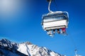 Skiers in a chairlift against blue sunny sky at ski resort