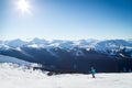 Skiers on a hill at the top of Blackcomb, 7th Heaven, with a view looking toward Whistler on a sunny day.