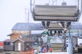 Skiers` legs on a cableway chair ski lift in cloudy snowy winter mountains close up