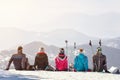 Skiers looking mountain`s landscape while sitting on snow, back