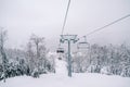 Skiers ride on four-seater chairlifts above snow-covered trees Royalty Free Stock Photo