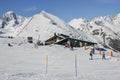 Skiers and snowboarders next to a wooden cabin in the Italian Alps during the winter, with copy space