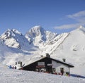 Skiers and snowboarders next to a wooden cabin in the Italian Alps during the winter, with copy space