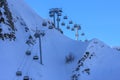 Skiers and snowboarders ride on chair ski lift at Gorky Gorod mountain ski resort in Sochi, Russia, against blue sky in the evenin Royalty Free Stock Photo
