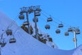 Skiers and snowboarders ride on chair ski lift at Gorky Gorod mountain ski resort in Sochi, Russia, against blue sky in the evenin Royalty Free Stock Photo