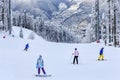 Skiers and snowboarders ride on ski slope in Sochi mountain ski resort on snowy winter mountain scenic background. Caucasus