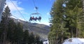 Skiers, snowboarders riding on a ski lift, transportation to mountain ski slopes resort