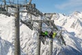 Skiers and snowboarders rise on a modern cable lift to a high mountain