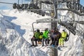 Skiers and snowboarders rise on a modern cable lift to a high mountain