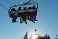 Skiers and snowboarders on ski lift against blue sky in the mountain at winter vacation Royalty Free Stock Photo