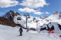 Skiers standing on snowy mountain cirque ski slope at sunny day against the chair lifts and blue sky winter background