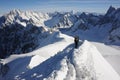 Skiers walking on mountain ridge covered with snow in French Alps in winter with beautiful panorama and blue sky Royalty Free Stock Photo