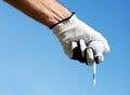 The skies the limit if you practice hard enough. A golfers hand holding his tee and golfball against a blue sky.