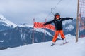 Skiing in the snow. One Asian girl sitting on ski lift by grabbing the rope and holding ski sticks. Vacation in Switzerland Royalty Free Stock Photo