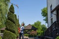 Skilful gardener using high-altitude hedge trimmer while shaping conifer tree in topiary garden. Royalty Free Stock Photo