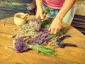 Skilful hands of girl putting blossoms of lavender into bouquet.