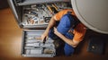 Skill on Display - Top view high angle of repairman with toolbox instruments lying down on the floor and fixing dishwasher in the