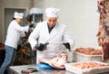 Butchery worker sawing beef ribs at cutting table