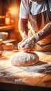 Skilled baker carefully kneading dough for baking bread in bakery with blurred background