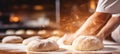 Skilled baker kneading dough in bakery, blur background with copy space bright photo