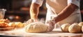 Skilled baker kneading dough in bakery for bread baking bright photo with blurred background