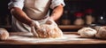 Skilled baker kneading dough for delicious bread on blurred background with text space.