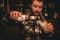 Bartender pouring grenadine syrup from bottle into glass with ice, preparing Tequila Sunrise cocktail Royalty Free Stock Photo