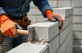 Skilled bricklayer in blue shirt lays brick with precision using hammer. Brick is placed in wall outline. Bricklaying process Royalty Free Stock Photo